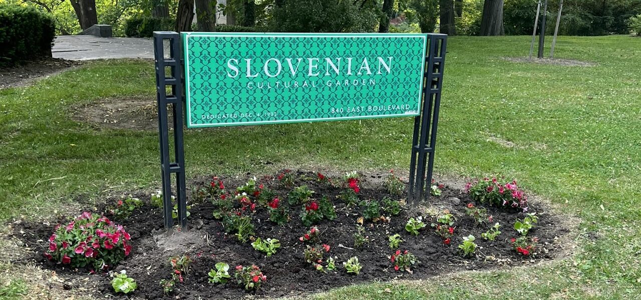 Slovenian cultural garden sign with pink and red flowers growing around it