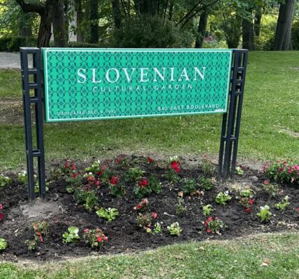 Slovenian cultural garden sign with pink and red flowers growing around it