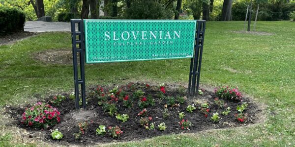 Slovenian cultural garden sign with pink and red flowers growing around it
