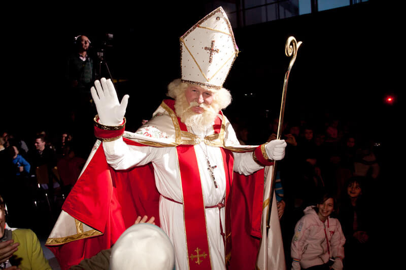 a man dressed as bishop nicholas waving to onlookers