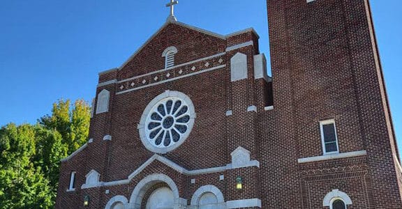 exterior of holy family parish, kansas, a large red brick building with white trim on a bright sunny cloudless day