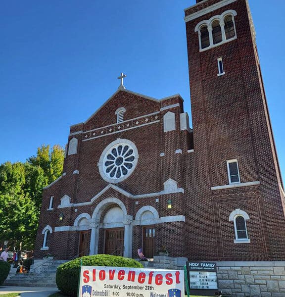 exterior of holy family parish, kansas, a large red brick building with white trim on a bright sunny cloudless day