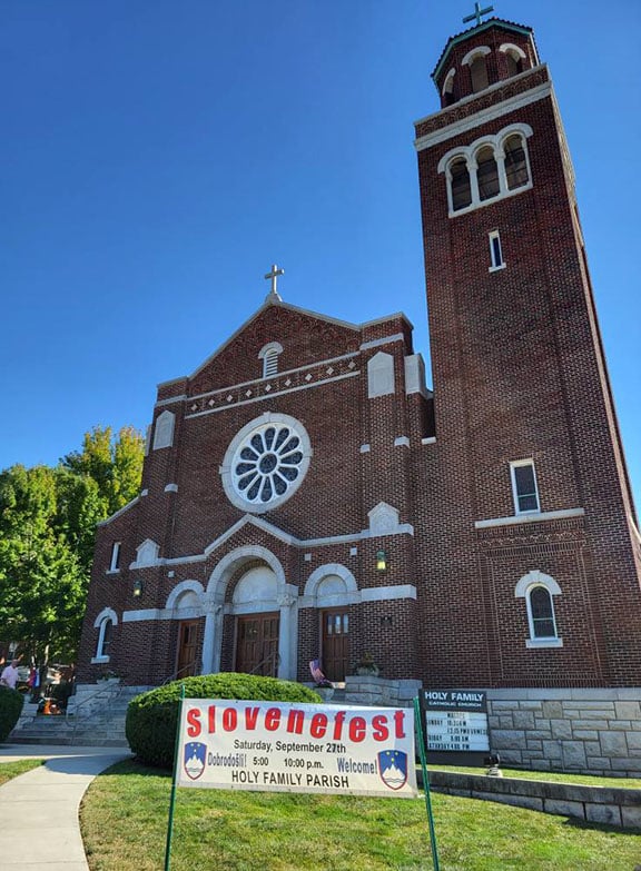 exterior of holy family parish, kansas, a large red brick building with white trim on a bright sunny cloudless day
