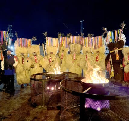 a group of Kurenti around some firepits at night time
