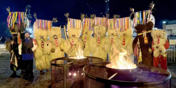 a group of Kurenti around some firepits at night time