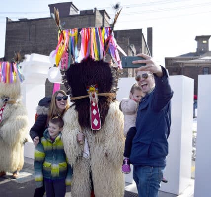 A family with young children pose for a photo with a Kurenti