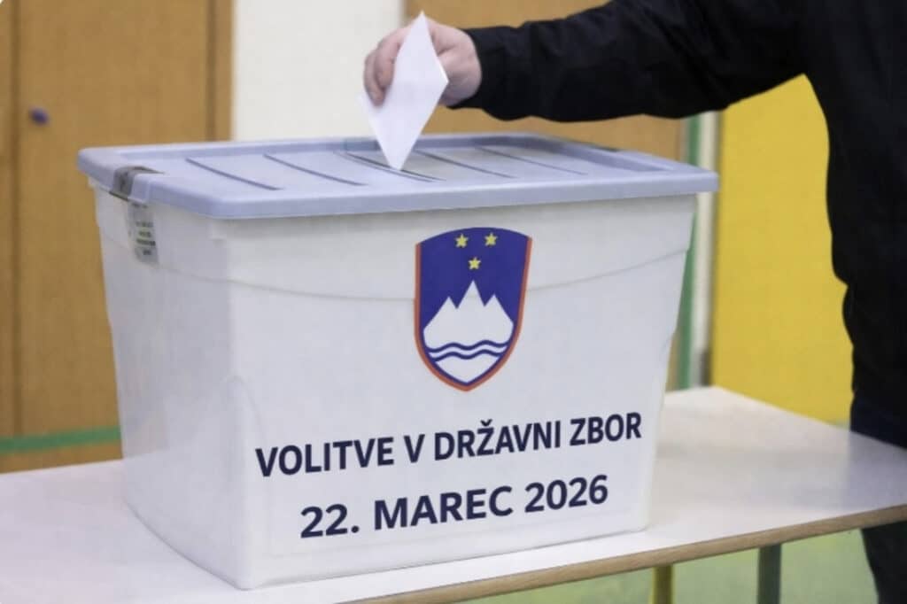a hand placing a voting ballot into a collection box