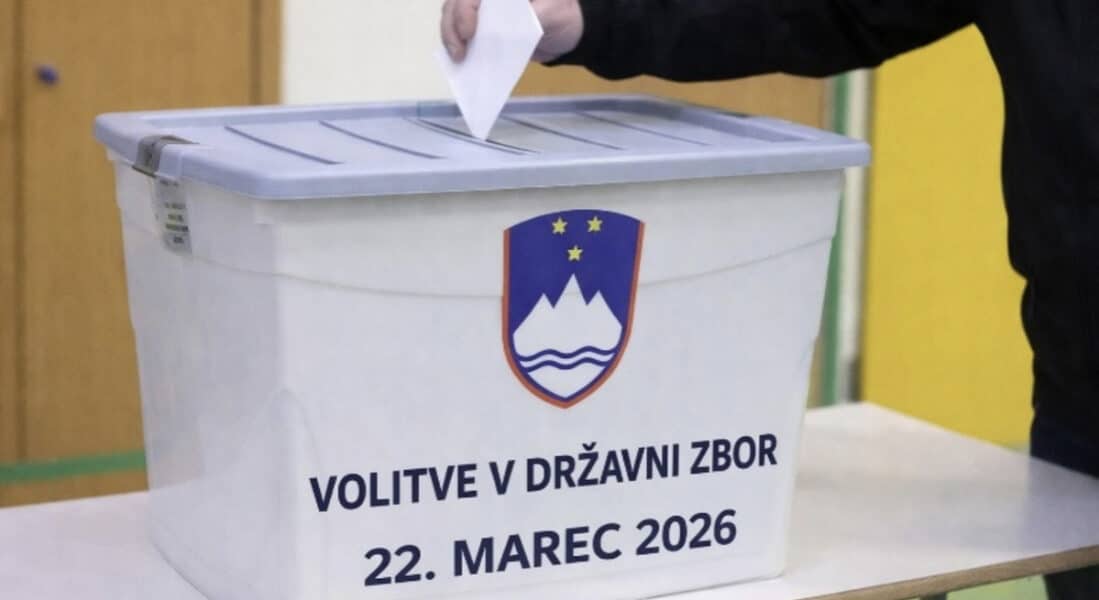 a hand placing a voting ballot into a collection box