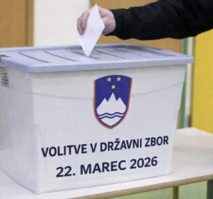 a hand placing a voting ballot into a collection box