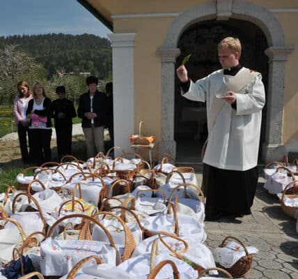 priest blessing food baskets outside of church on a sunny holy saturday