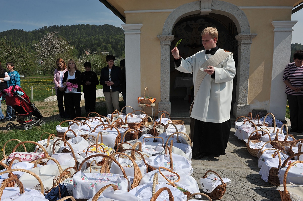 priest blessing food baskets outside of church on a sunny holy saturday
