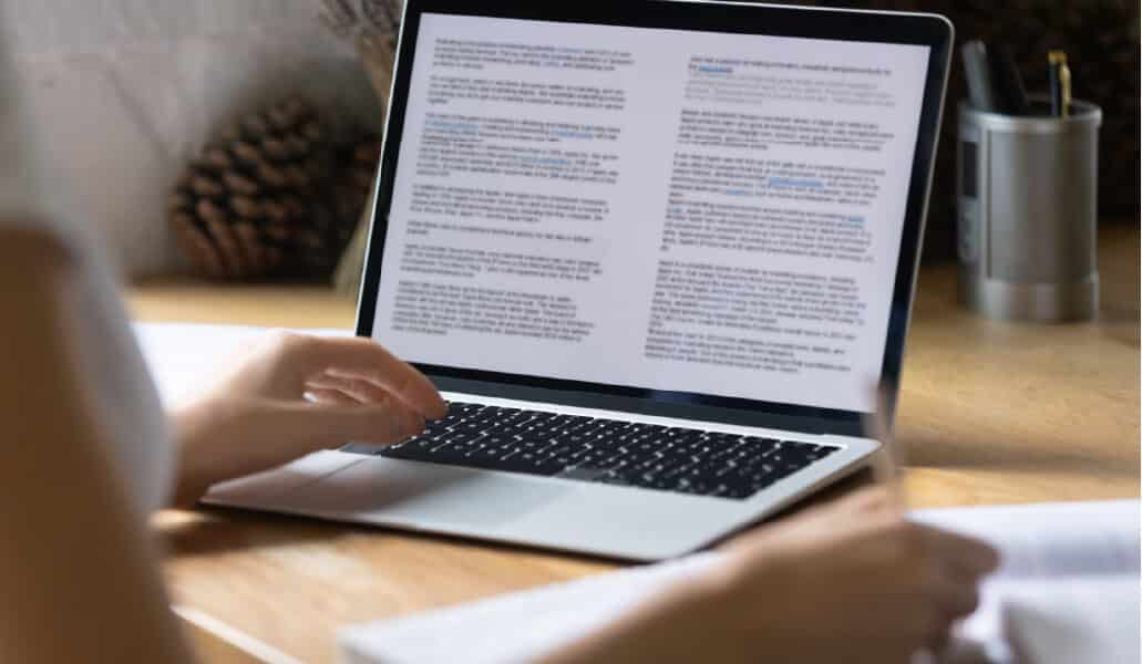 person typing on laptop computer with article on screen