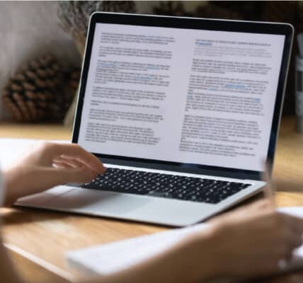 person typing on laptop computer with article on screen