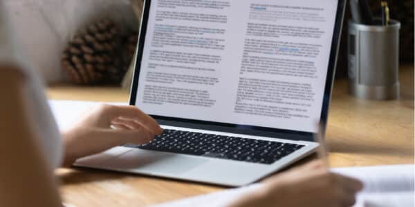 person typing on laptop computer with article on screen