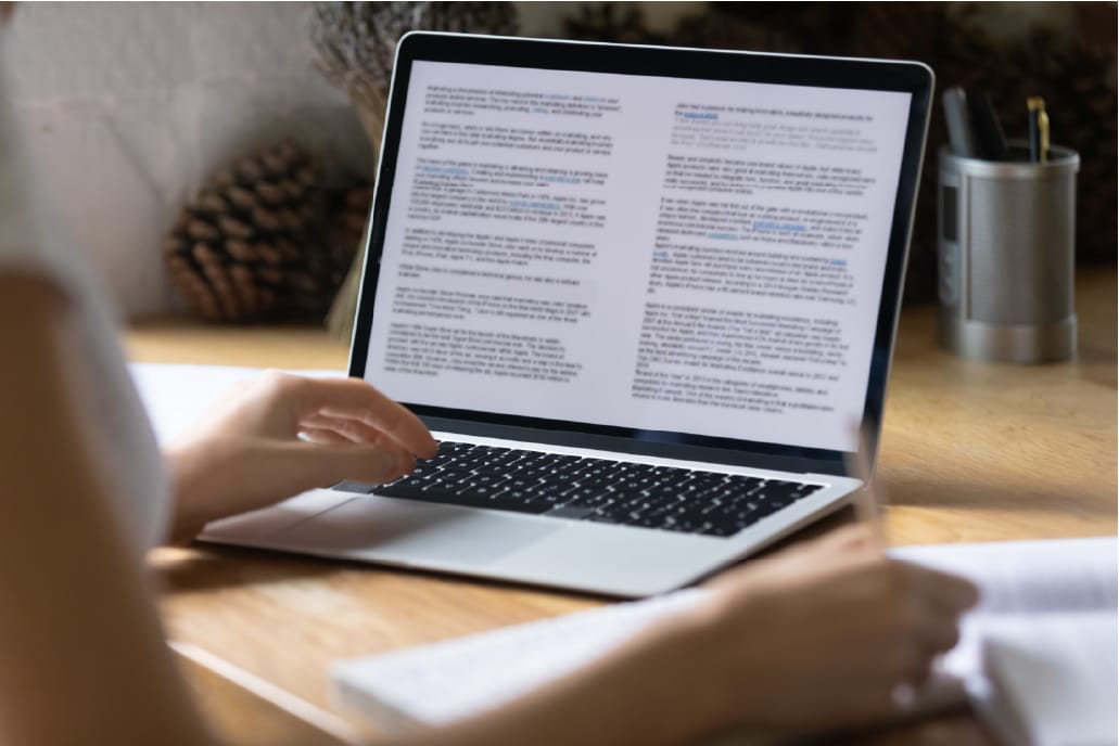 person typing on laptop computer with article on screen
