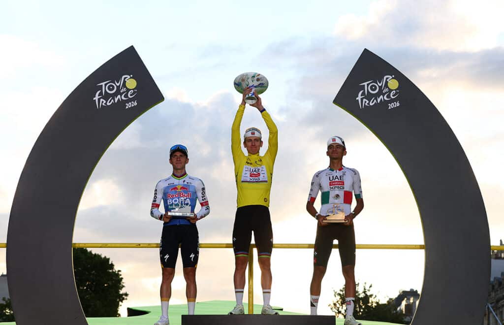 Cycling - Tour de France - Stage 21 - Paris, France - July 26, 2026 UAE Team Emirates XRG's Tadej Pogacar celebrates on the podium while wearing the yellow jersey after winning the Tour de France, alongside UAE Team Emirates XRG's Isaac Del Toro wearing the white jersey and Red Bull - BORA - hansgrohe's Remco Evenepoel REUTERS/Gonzalo Fuentes