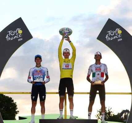 Cycling - Tour de France - Stage 21 - Paris, France - July 26, 2026 UAE Team Emirates XRG's Tadej Pogacar celebrates on the podium while wearing the yellow jersey after winning the Tour de France, alongside UAE Team Emirates XRG's Isaac Del Toro wearing the white jersey and Red Bull - BORA - hansgrohe's Remco Evenepoel REUTERS/Gonzalo Fuentes