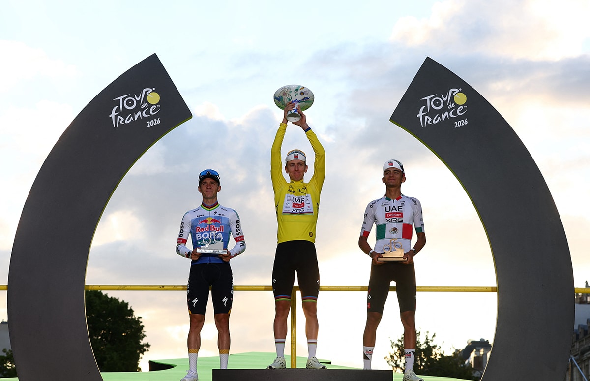 Cycling - Tour de France - Stage 21 - Paris, France - July 26, 2026 UAE Team Emirates XRG's Tadej Pogacar celebrates on the podium while wearing the yellow jersey after winning the Tour de France, alongside UAE Team Emirates XRG's Isaac Del Toro wearing the white jersey and Red Bull - BORA - hansgrohe's Remco Evenepoel REUTERS/Gonzalo Fuentes